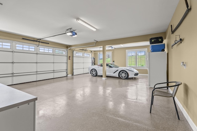 garage featuring a garage door opener, baseboards, and freestanding refrigerator