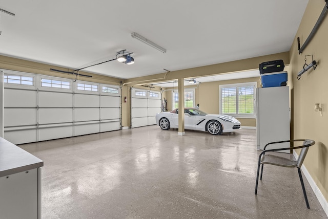 garage featuring a garage door opener, freestanding refrigerator, and baseboards