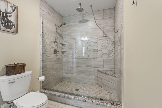 bathroom featuring toilet and a tile shower