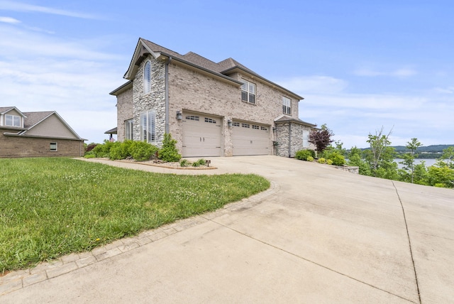 view of side of home with an attached garage, driveway, brick siding, a lawn, and stone siding