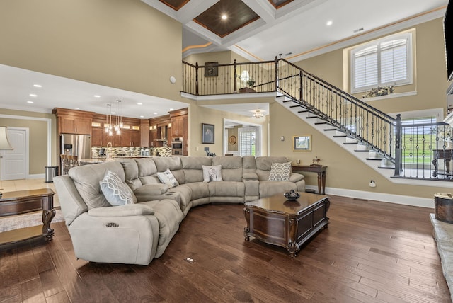 living area with crown molding, a towering ceiling, stairway, baseboards, and a chandelier