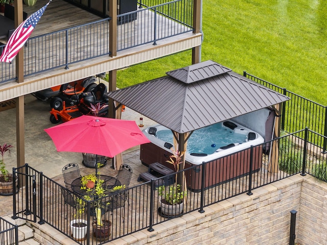 deck featuring a hot tub, a patio area, and a yard