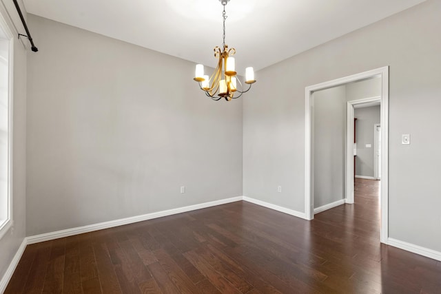 unfurnished room with baseboards, dark wood-style flooring, and a chandelier