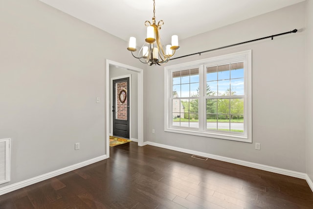 unfurnished dining area featuring baseboards, visible vents, an inviting chandelier, and dark wood-type flooring