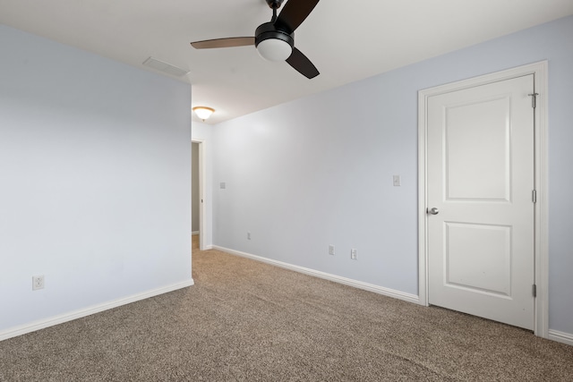 carpeted spare room featuring visible vents, a ceiling fan, and baseboards