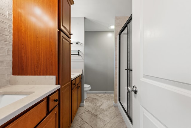 bathroom featuring a shower stall, toilet, vanity, and baseboards
