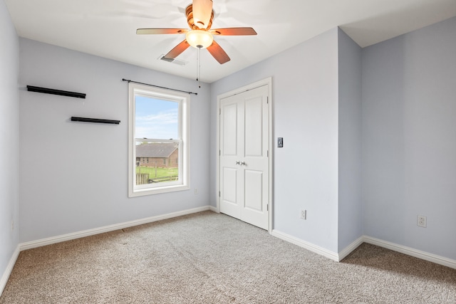 carpeted empty room with visible vents, baseboards, and ceiling fan