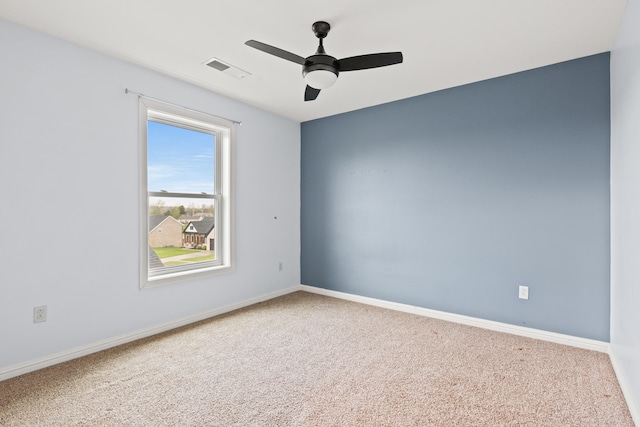 carpeted spare room with visible vents, baseboards, and ceiling fan