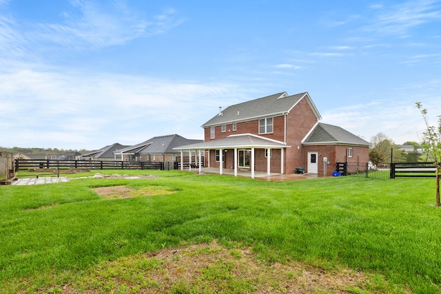 back of house with a lawn, a fenced backyard, brick siding, and a patio