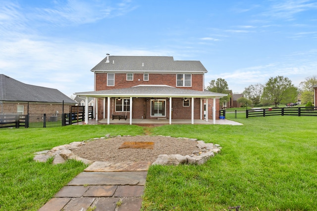 rear view of property featuring brick siding, fence, a yard, and a patio