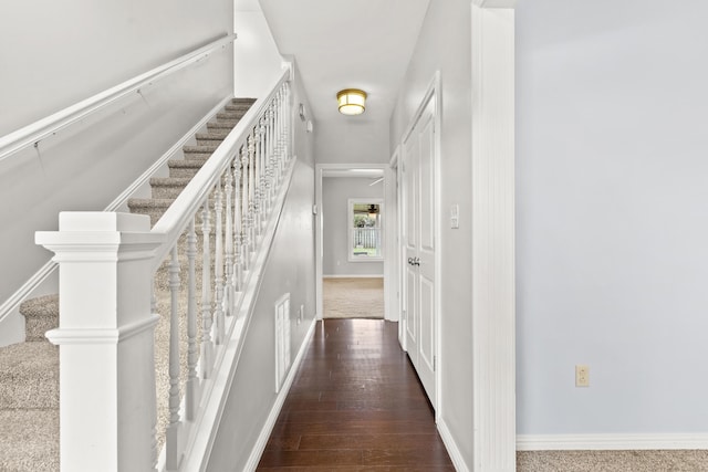 corridor with baseboards, wood finished floors, stairs, and visible vents