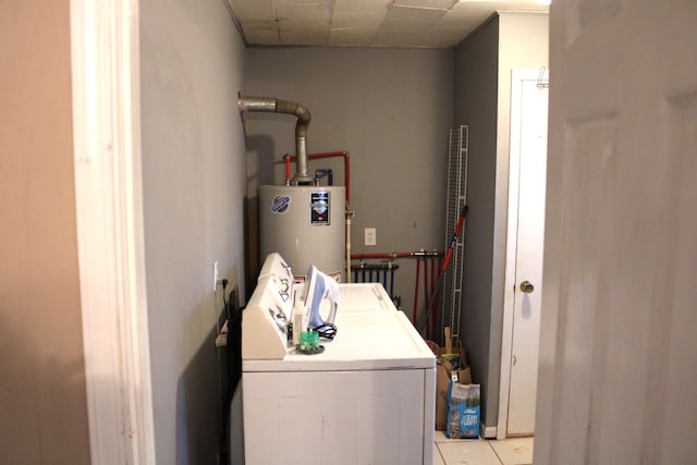 clothes washing area featuring water heater, washing machine and clothes dryer, and light tile patterned floors