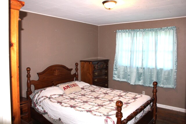 bedroom with wood finished floors, baseboards, and ornamental molding