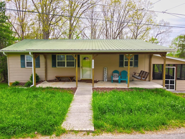 single story home with a front lawn, metal roof, and a sunroom