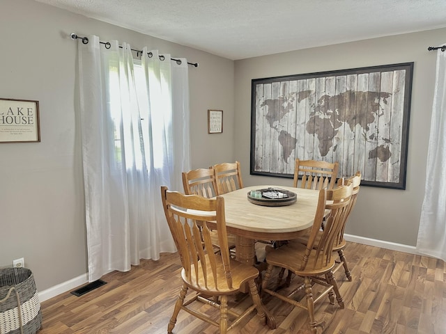 dining room featuring wood finished floors, visible vents, and baseboards