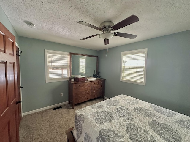 carpeted bedroom featuring a textured ceiling, multiple windows, ceiling fan, and baseboards