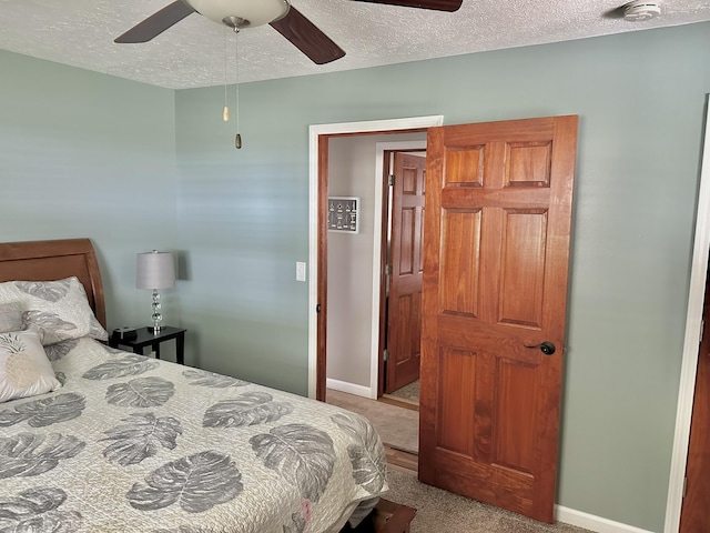 bedroom featuring a textured ceiling, ceiling fan, carpet, and baseboards