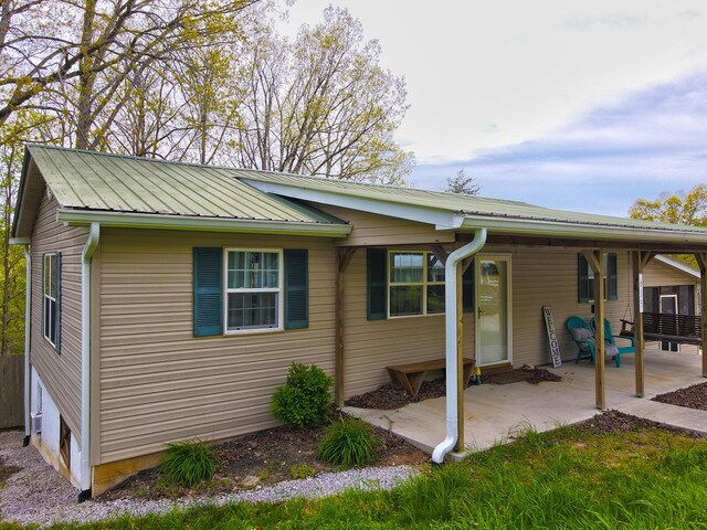 back of property featuring a patio and metal roof