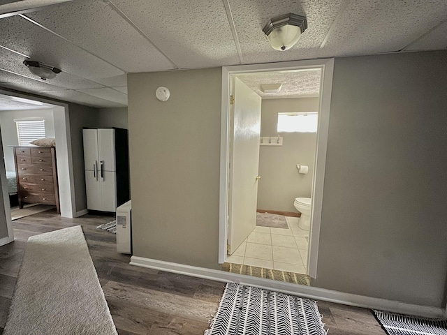 bathroom featuring toilet, a healthy amount of sunlight, a drop ceiling, and baseboards