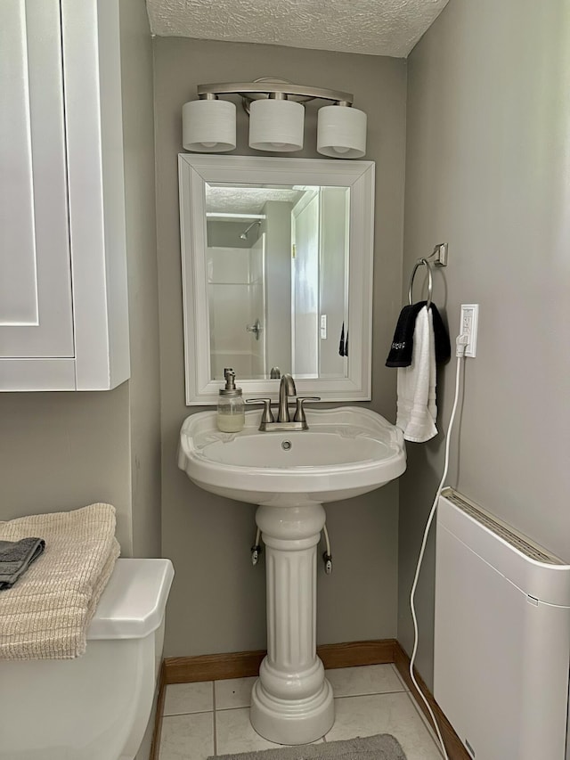 bathroom featuring tile patterned floors, a textured ceiling, walk in shower, and baseboards