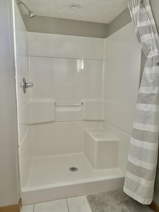 full bathroom featuring a stall shower, tile patterned flooring, and a textured ceiling
