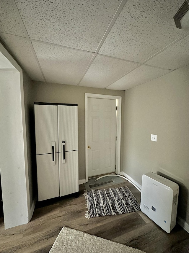 entrance foyer with a drop ceiling, wood finished floors, and baseboards