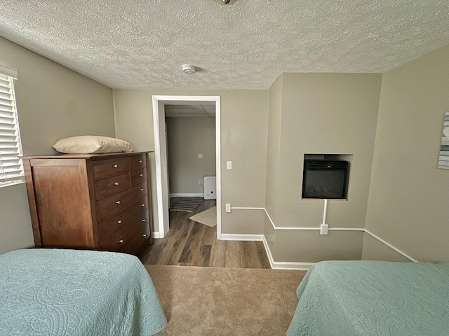 bedroom featuring dark wood-style flooring, baseboards, and a textured ceiling