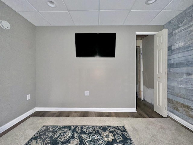 interior space with wood finished floors, a drop ceiling, and baseboards