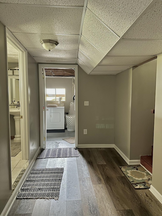 hall with baseboards, washer / dryer, wood finished floors, and a drop ceiling