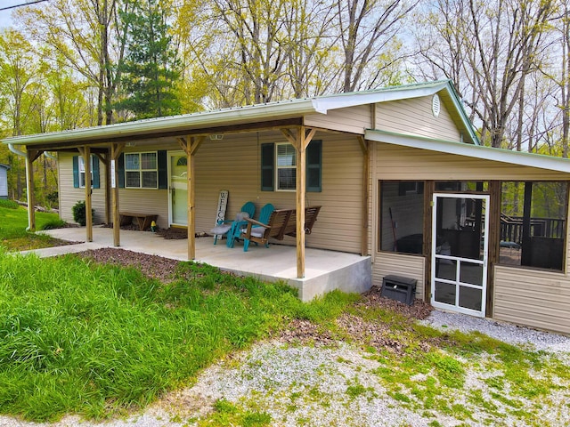 rear view of property with a sunroom and a patio area