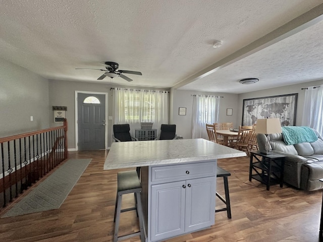 kitchen with open floor plan, a kitchen bar, light countertops, and a textured ceiling