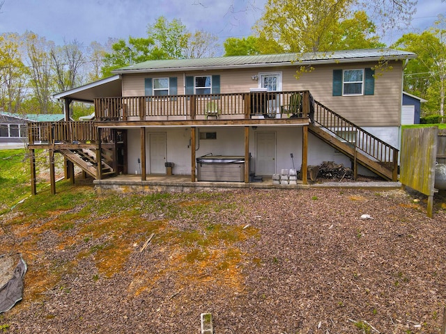 back of house featuring stairway, a wooden deck, a hot tub, and metal roof