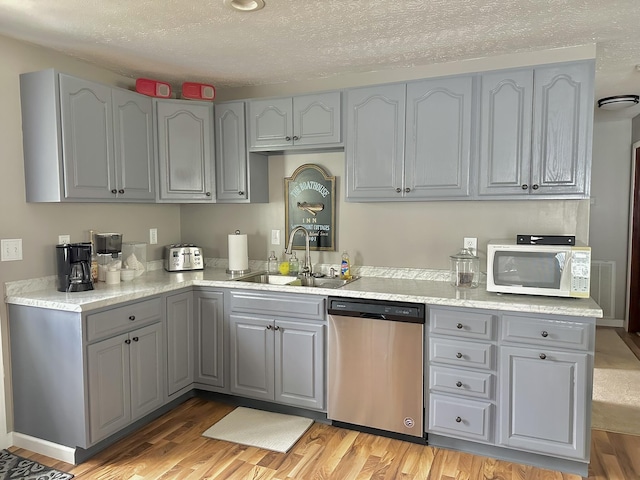 kitchen featuring a sink, dishwasher, white microwave, and gray cabinets
