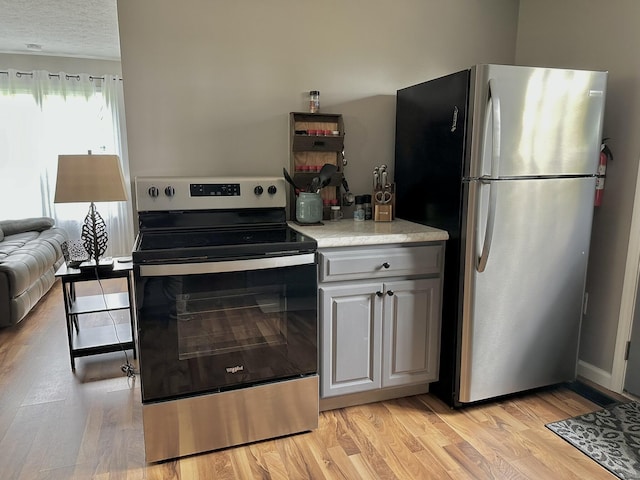 kitchen with stainless steel appliances, light countertops, and light wood-style flooring