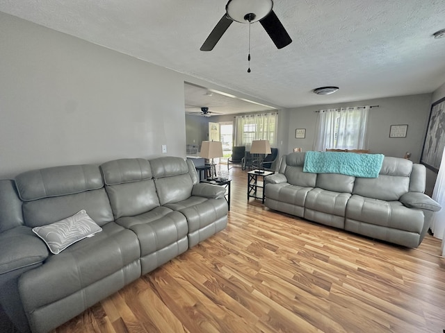 living area featuring a textured ceiling, light wood-style floors, and a ceiling fan