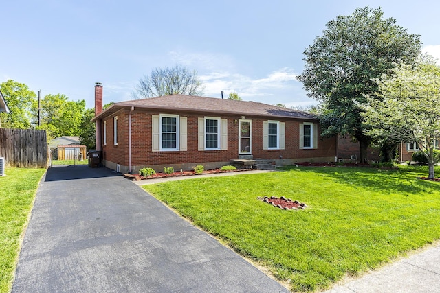 single story home with a front lawn, brick siding, aphalt driveway, a chimney, and fence