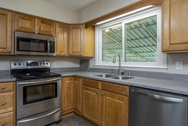 kitchen with brown cabinetry, appliances with stainless steel finishes, and a sink