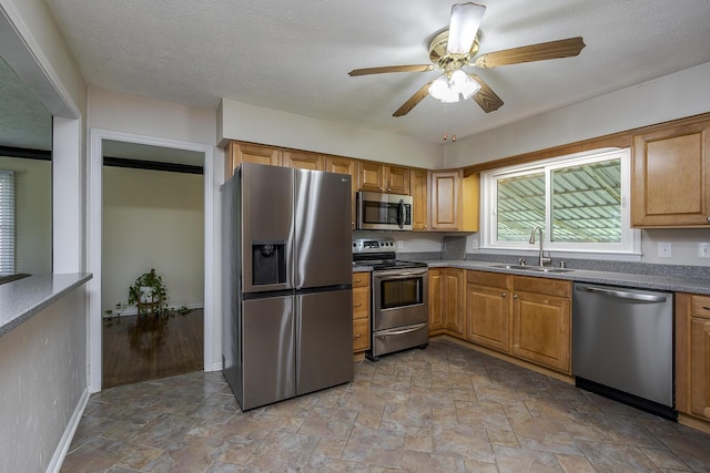 kitchen featuring stone finish flooring, stainless steel appliances, ceiling fan, and a sink