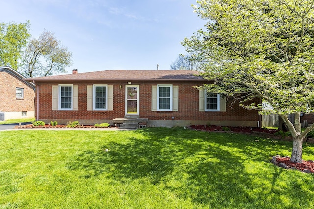 ranch-style home featuring a chimney, brick siding, and a front yard