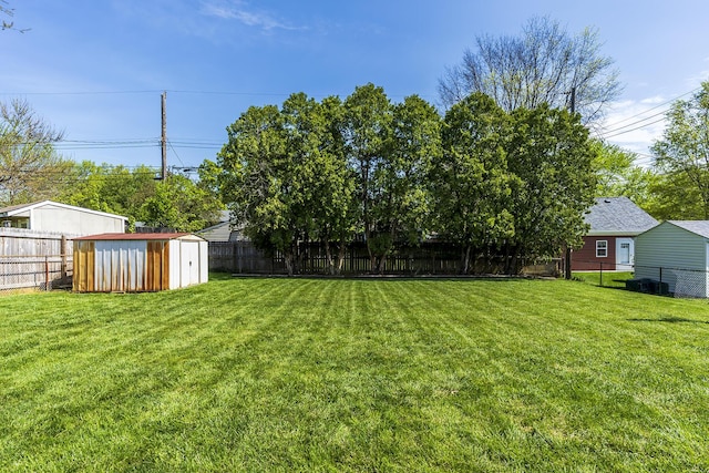 view of yard with a fenced backyard, an outbuilding, and a storage shed