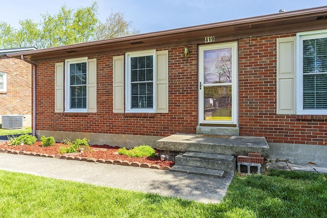 doorway to property featuring central AC unit and brick siding