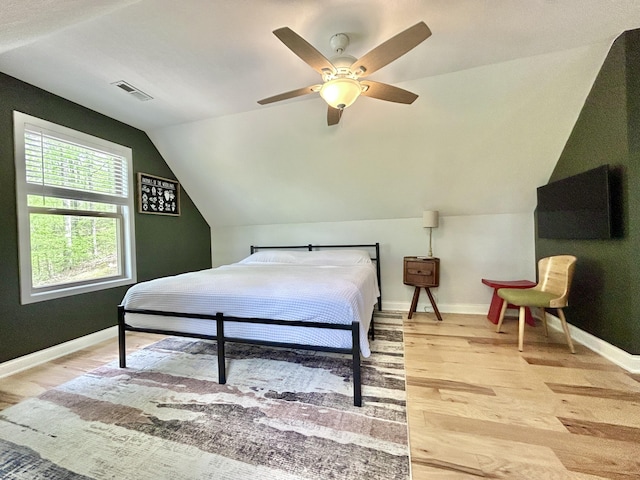 bedroom with visible vents, light wood-style flooring, baseboards, and vaulted ceiling