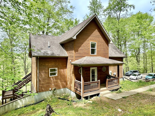 back of property with a porch, stairs, and roof with shingles