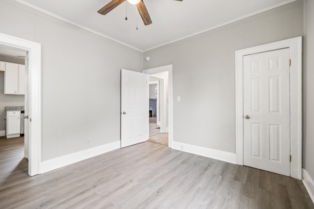unfurnished bedroom featuring baseboards, light wood-style floors, and ornamental molding