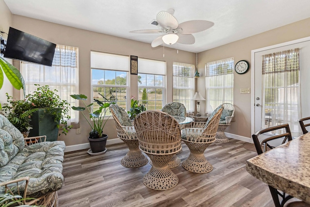 dining space with baseboards, a ceiling fan, and wood finished floors