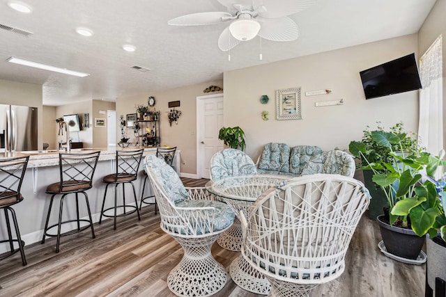 dining area with baseboards, ceiling fan, wood finished floors, and visible vents