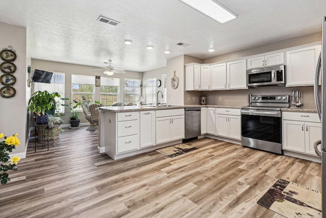 kitchen with visible vents, a peninsula, a sink, and appliances with stainless steel finishes