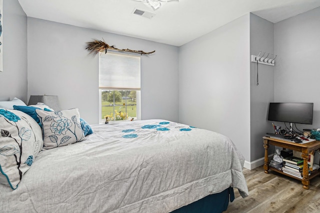 bedroom with baseboards, wood finished floors, and visible vents