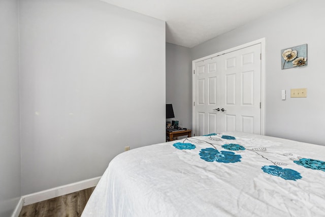 bedroom featuring baseboards, dark wood finished floors, and a closet
