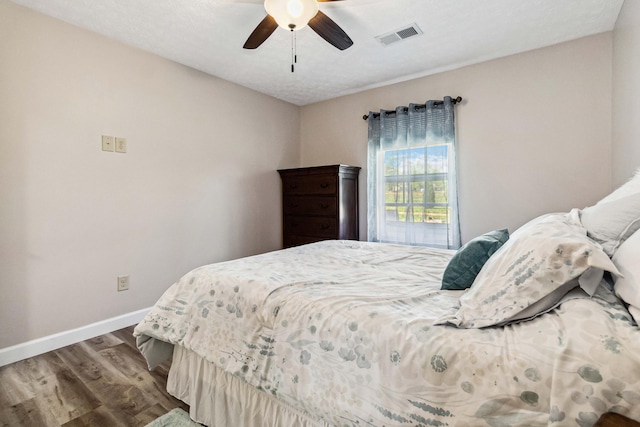 bedroom with a ceiling fan, baseboards, visible vents, and wood finished floors